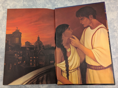 An open book showing two illustrated figures in white robes on the right page and a dark architectural scene with glowing orange lanterns on the left page, photographed against a mottled light gray background.