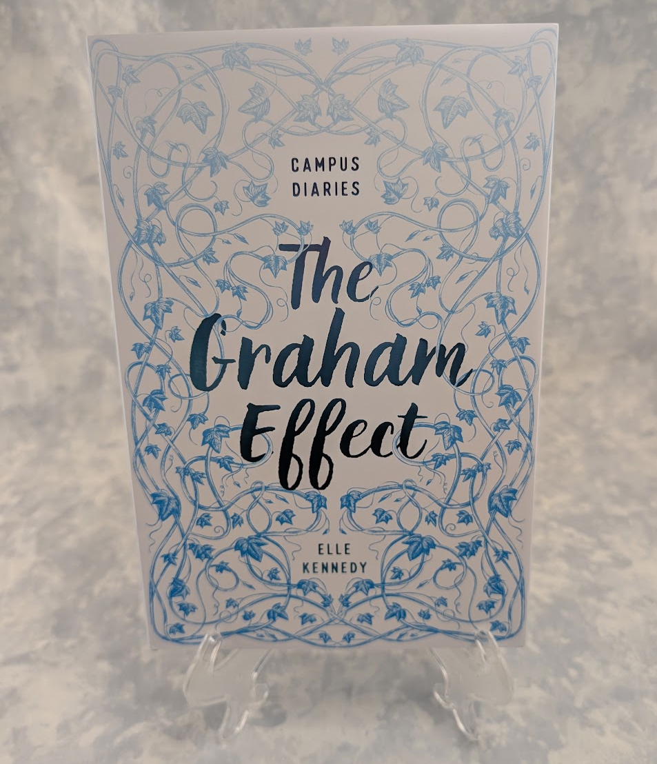 The book cover of 'The Graham Effect' by Elle Kennedy, part of the Campus Diaries series, displayed on a clear plastic stand against a textured gray background.