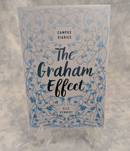The book cover of 'The Graham Effect' by Elle Kennedy, part of the Campus Diaries series, displayed on a clear plastic stand against a textured gray background.