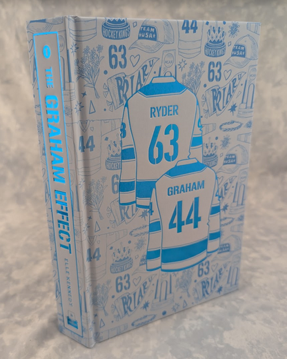 A hardcover book titled 'The Graham Effect', featuring a light blue and white hockey-themed cover with illustrated jerseys, numbers 63 and 44, and doodled icons like hats and trophies.